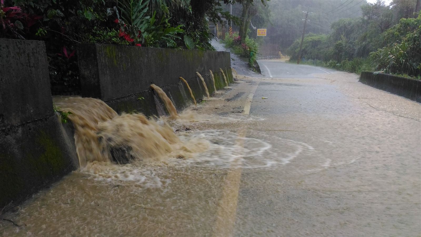 豪雨中山區道路旁排水口湧出泥水